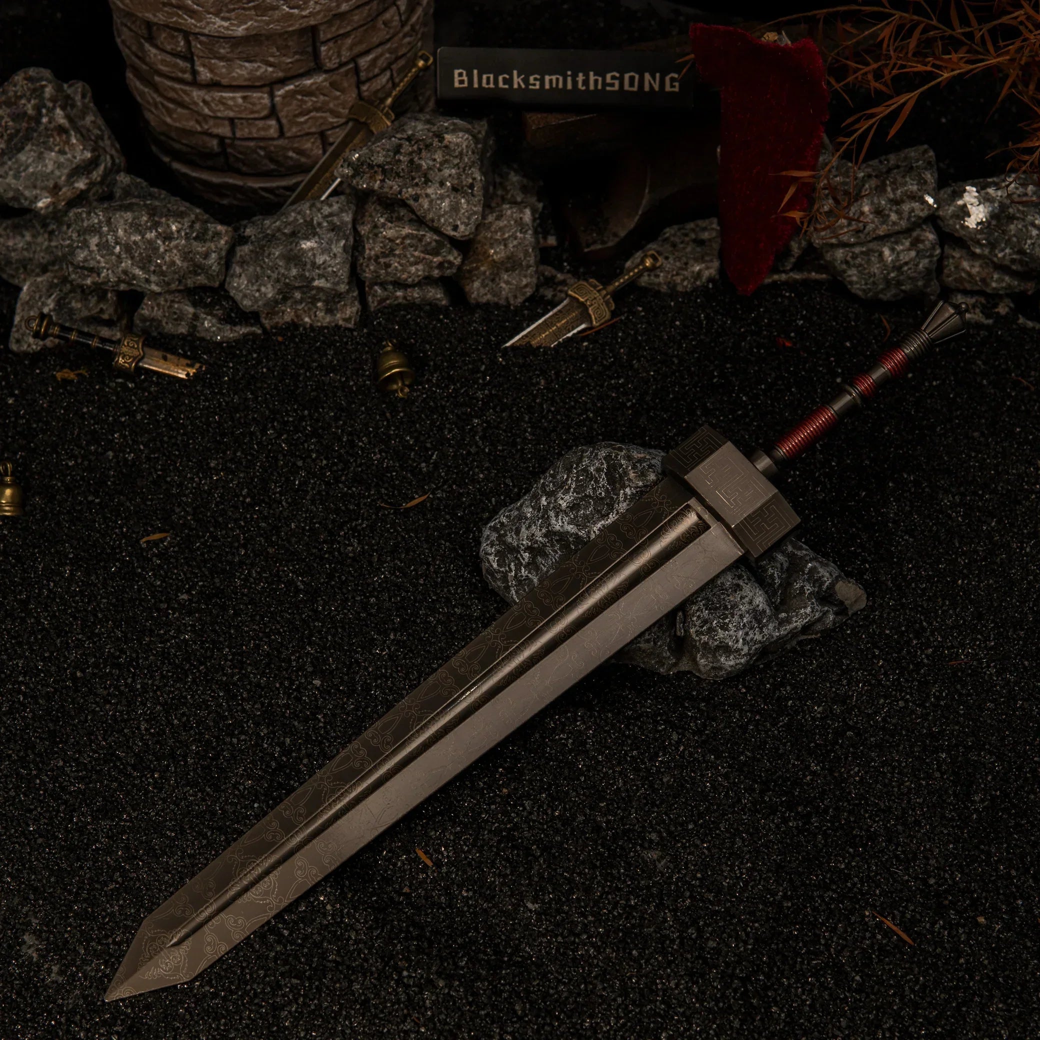 Greatsword metal replica resting diagonally on dark rocks, surrounded by black sand, scattered miniature broken swords, and small brass bells in a diorama setting.