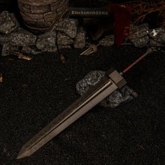 Greatsword metal replica resting diagonally on dark rocks, surrounded by black sand, scattered miniature broken swords, and small brass bells in a diorama setting.