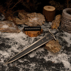 Greatsword of Solitude replica resting on rocks in a snowy setting with dry brown branches and a miniature stone well in the background.