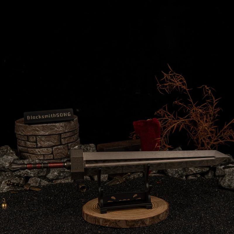 Greatsword miniature resting horizontally on a small black stand with a wooden base, surrounded by dark rocks and miniature battlefield debris.