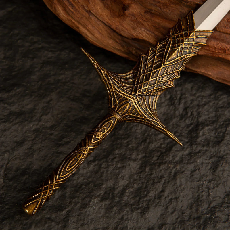 Close-up macro shot of the golden lattice hilt of the Leda's Sword replica resting on dark slate.