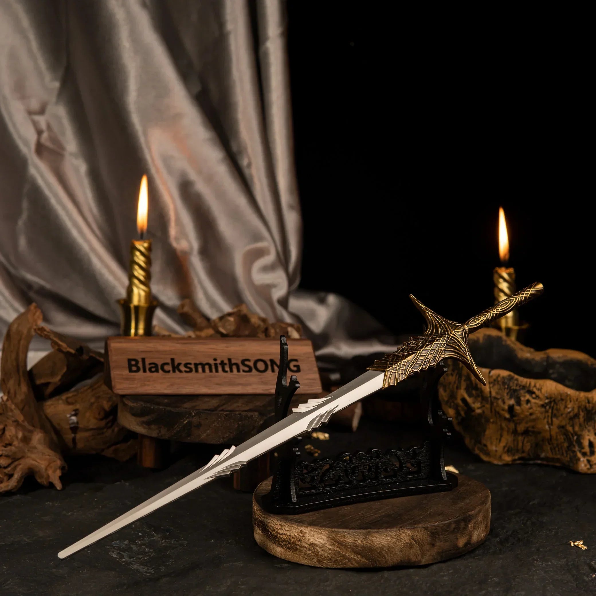 Leda's Sword metal replica displayed horizontally on a large black stand with dark silk fabric and lit candles in the background.