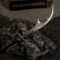 Macro close-up shot of the silver crescent blade of Loretta's War Sickle replica, showcasing intricate floral engravings resting on a dark rock.