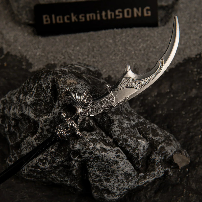 Macro close-up shot of the silver crescent blade of Loretta's War Sickle replica, showcasing intricate floral engravings resting on a dark rock.