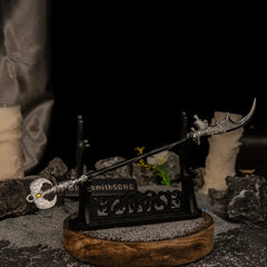 Loretta's War Sickle metal replica displayed horizontally on a large black decorative stand over a circular wooden base in a dark setting.