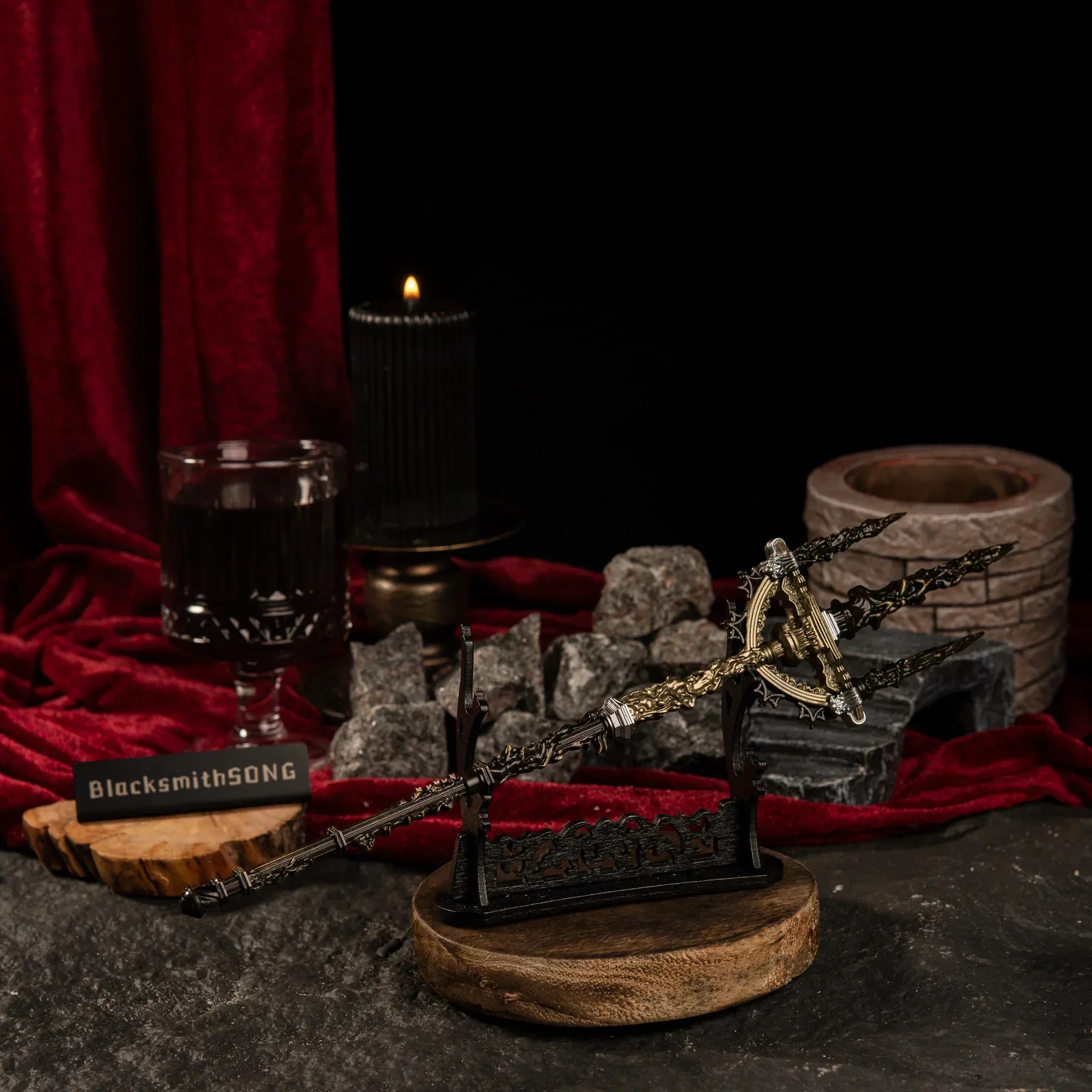 The Mohgwyn's Sacred Spear metal replica displayed horizontally on a large black decorative sword stand over a dark stone surface.