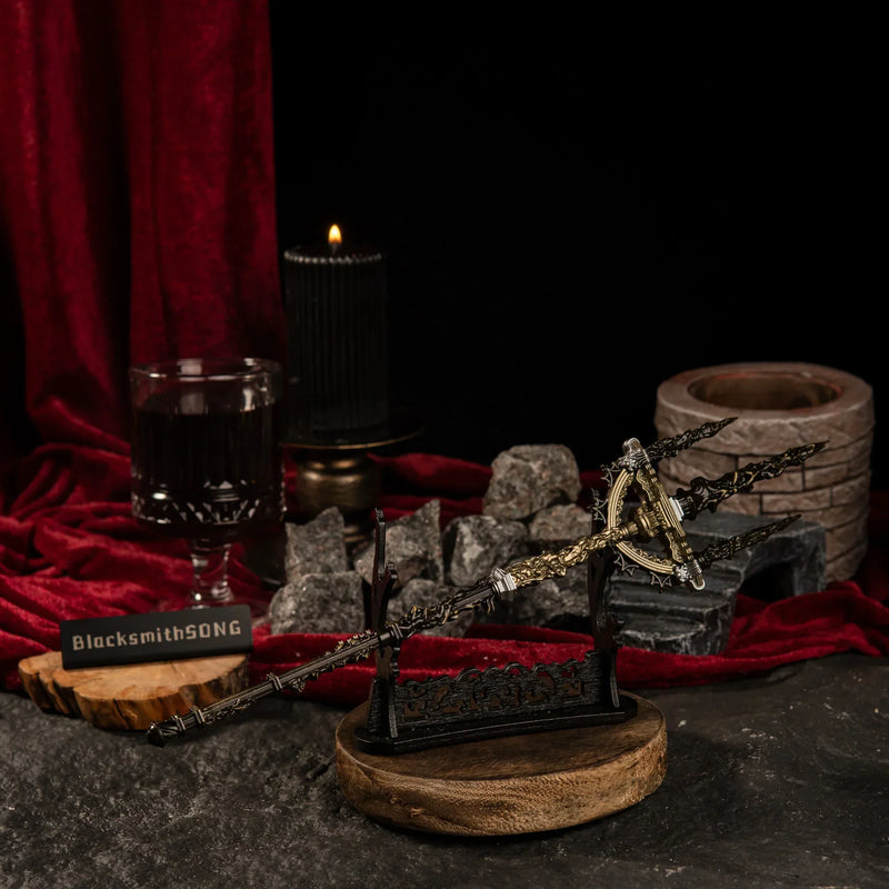 The Mohgwyn's Sacred Spear metal replica displayed horizontally on a large black decorative sword stand over a dark stone surface.