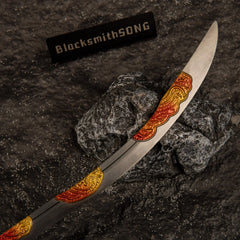 Detailed view of the metallic curved blade of the Nomad's Kilij replica, showcasing intricate engravings painted in a yellow and red fire gradient.