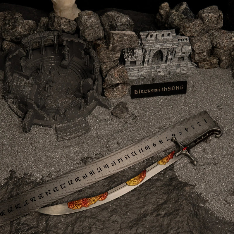 Nomad's Kilij metal replica placed next to a measuring ruler on grey sand, indicating a total length of approximately 26 centimeters.