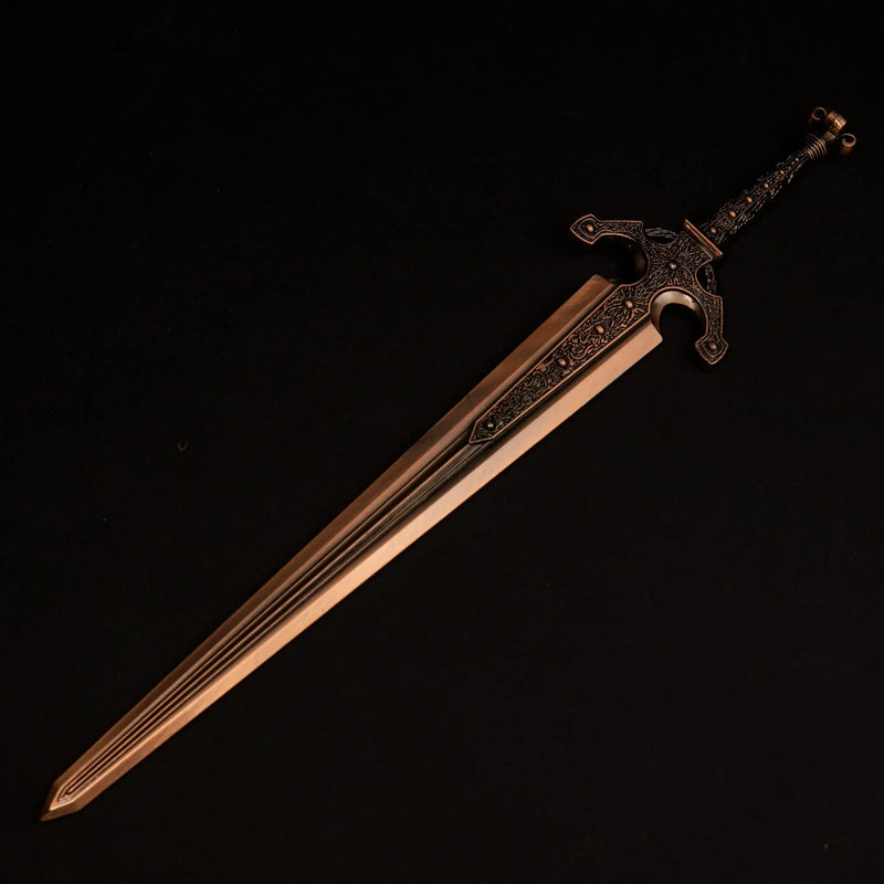 Solid metal replica of Ordovis's Greatsword from Elden Ring, featuring a red-tinged gold finish, isolated on a black background.