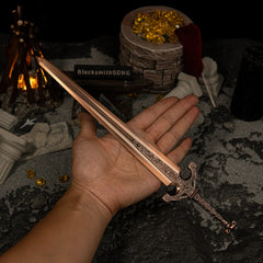 A hand holding the 30cm Ordovis's Greatsword metal replica to demonstrate its heavy scale, set against a dark background with stone pillars.