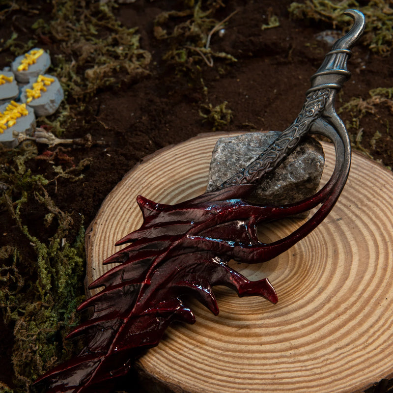 Close-up of the Reduvia metal miniature's organic bone-like handle and curved silver hilt.