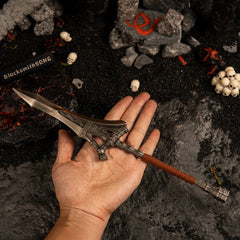 A hand holding the 30cm Serpent-Hunter metal spear replica to show its scale, set against a dark background with miniature skulls.