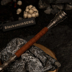 Close-up detail of the brown wrapped handle and textured metallic pommel of the Serpent-Hunter miniature weapon.