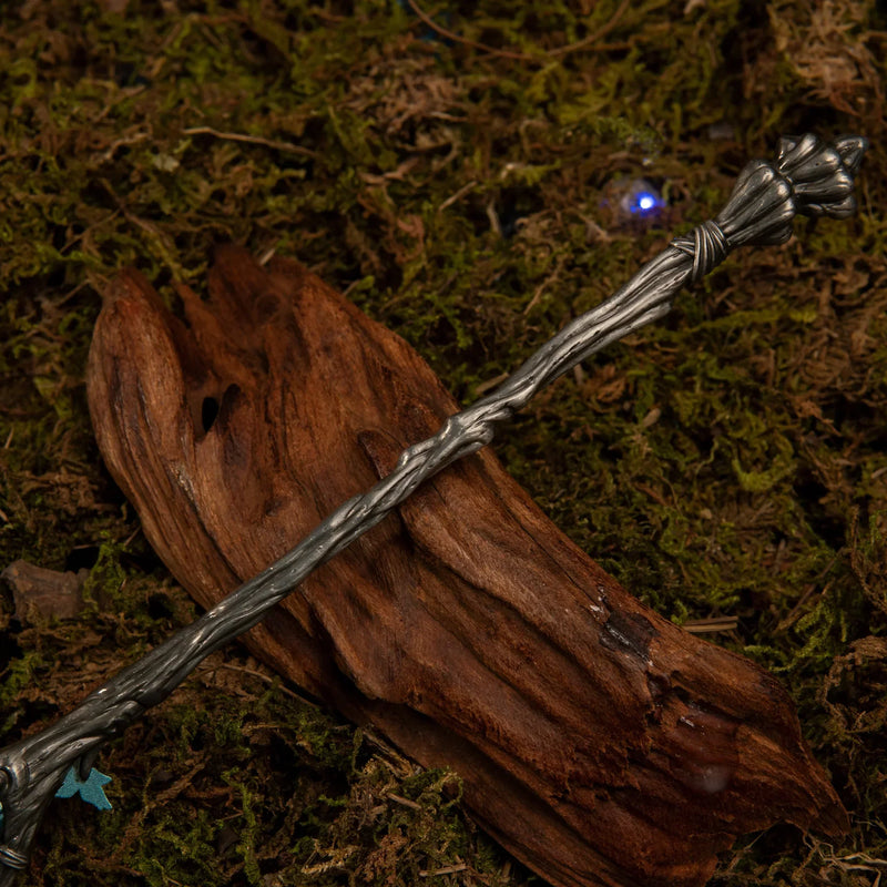 Detailed view of the lower grey metallic handle of the Spear of the Dreaming replica, sculpted to resemble twisted, ancient tree branches.