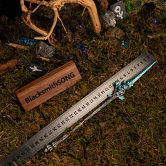 Spear of the Dreaming metal replica placed next to a measuring ruler on green moss, indicating a total length of approximately 30 centimeters.