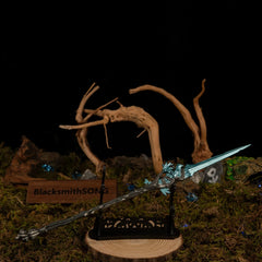 Spear of the Dreaming metal spear displayed horizontally on a large black decorative stand over a circular wooden base in a mossy diorama setting.
