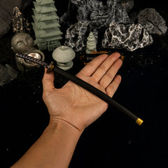 A hand holding the 25cm Star Shadow metal katana replica to show its scale, with a Zen garden diorama in the blurred background.
