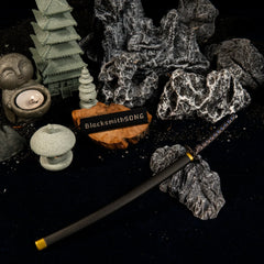 Angled overhead view of the Star Shadow katana replica in a dark, peaceful miniature rock garden setting with lit candles.