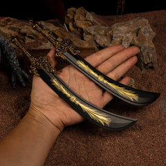 A hand holding the pair of Starscourge Greatsword metal replicas to show their scale, set against a background of red sand and dark rocks.
