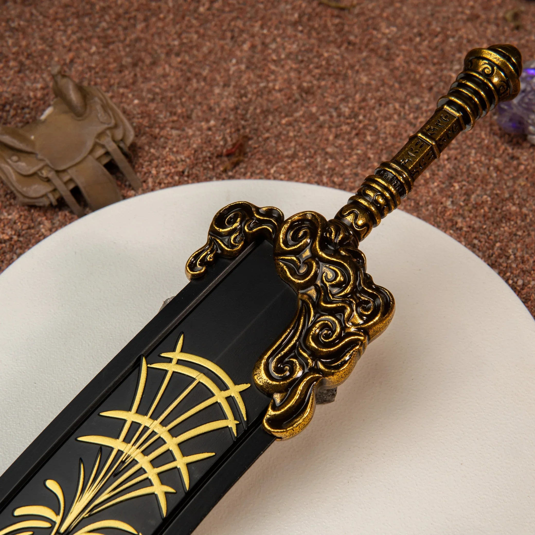 Close-up of the Starscourge Greatsword metal miniature's hilt, highlighting the engraved gold filigree patterns.