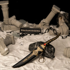 Catspaw Dagger replica — sheathed in its scabbard with keyring clasp, among fallen ruins.