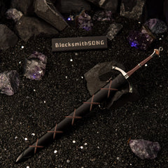 Dawn Sword replica — sheathed in its cross-laced black scabbard on dark sand.