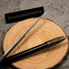 Needle replica — slim blade and black scabbard laid across wood.
