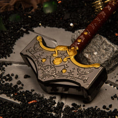 Mjolnir replica — hammer head close-up showing the rune engraving and gold studs.