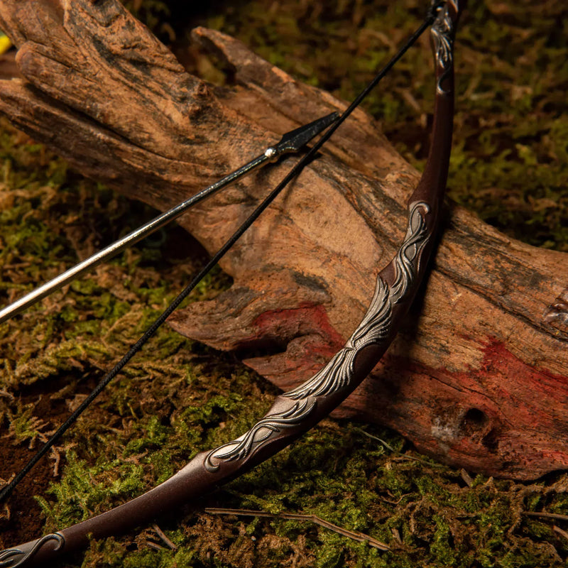 Bow of the Galadhrim replica — vine-carved bow stave leaning against a mossy log with its arrow.