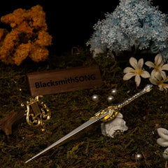 Galadriel's Dagger replica (22cm die-cast zinc alloy dagger) — resting beside a small gilded lyre in a two-toned garden set, by BlacksmithSONG.