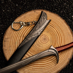 Orcrist replica — hooked crossguard and red-wrapped grip on a wood slice.