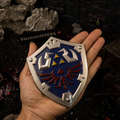 Hylian Shield replica (12cm die-cast zinc alloy shield) — held in hand for scale.