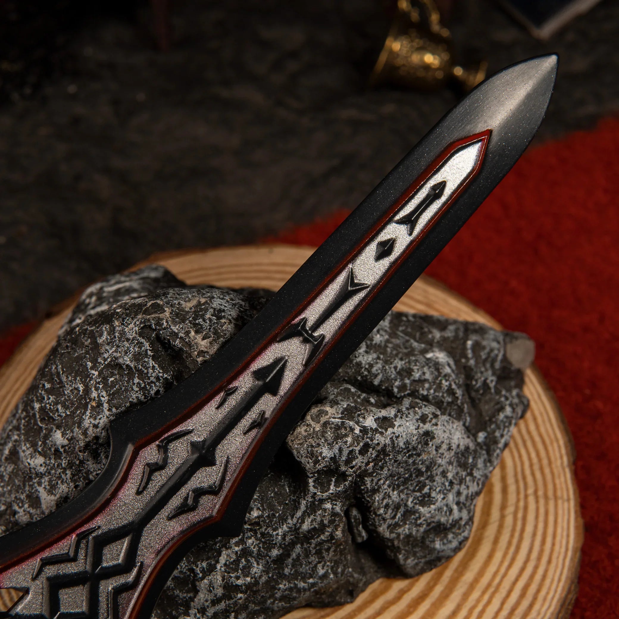 Detailed view of the obsidian black and silver blade of the 20.5cm Zelda Royal Guard's Claymore miniature, resting on a dark rock with a red carpet background.