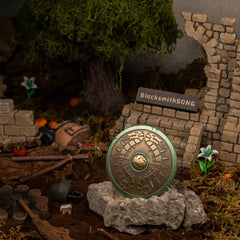 Traveler's Shield replica (7cm die-cast zinc alloy shield) — propped on a rock in a handcrafted raided-camp diorama, by BlacksmithSONG.