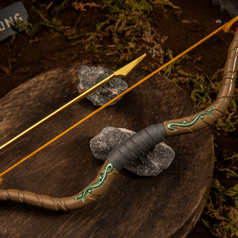 Close-up shot of the Zelda Wooden Bow replica's center grip, highlighting the sculpted dark leather texture, green vine motifs, and the nocked golden arrow resting on a wooden slice.